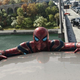 Spider-man hanging on to a car.